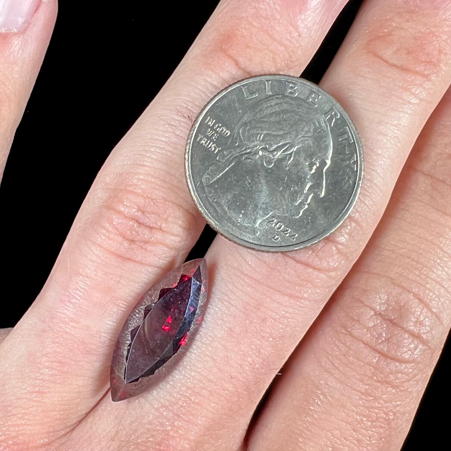 A loose, marquise cut cuprite gemstone.  The stone is a deep, crimson red color.