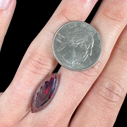 A loose, marquise cut cuprite gemstone.  The stone is a deep, crimson red color.