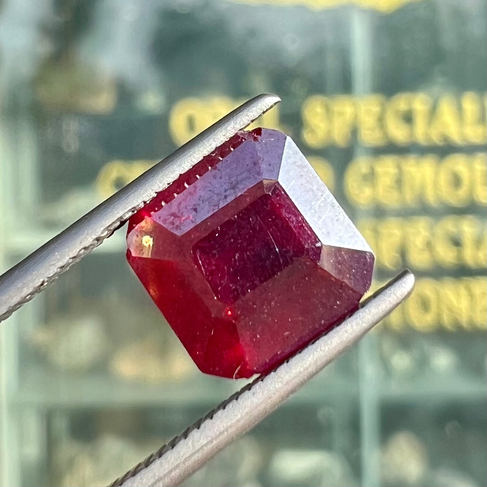 A loose, modified Asscher cut cuprite gemstone.  The stone is a deep, crimson red color and has several chips along the girdle.