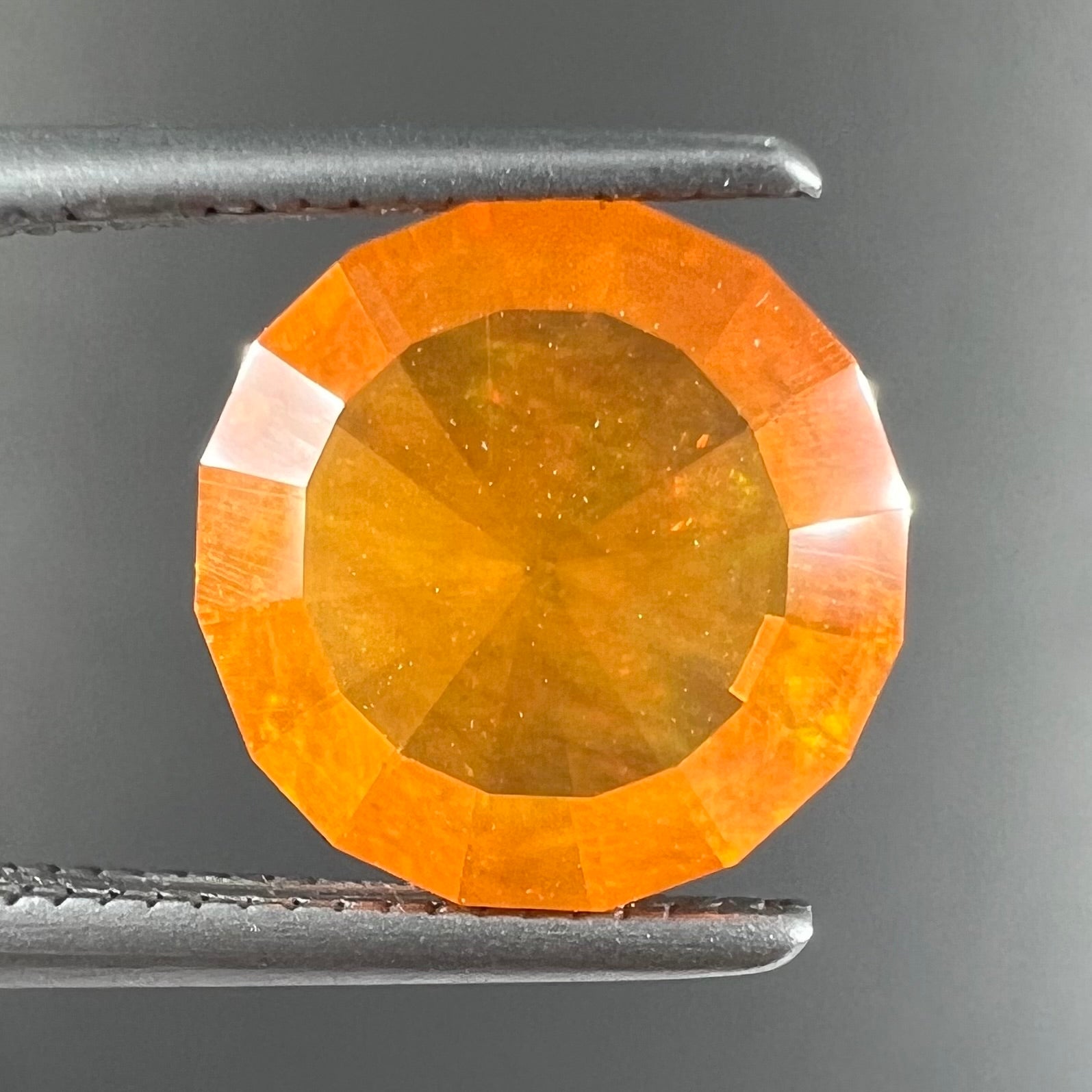 A loose, round faceted cut fire opal from Mexico.  The body color is yellowish orange with red, green, and yellow fire.