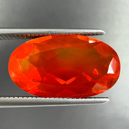 A loose, faceted oval cut Mexican fire opal stone.  The stone is a bright orange color.