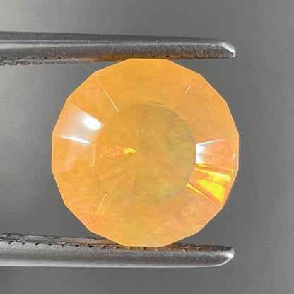 A loose, faceted round cut fire opal from Mexico.  The stone is yellow orange in body color.