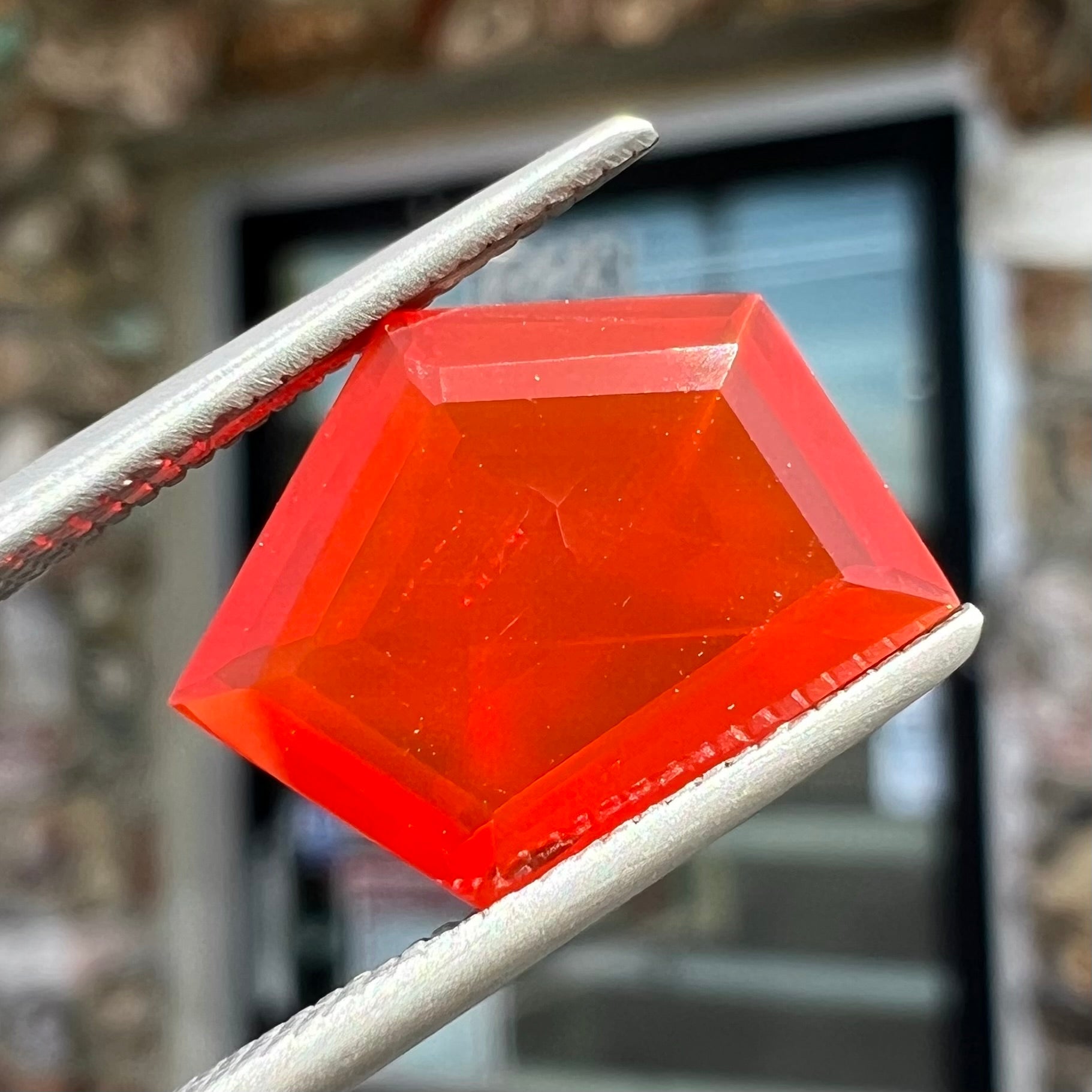 A loose, faceted freeform cut Mexican fire opal gemstone.  The stone is a cherry red color.