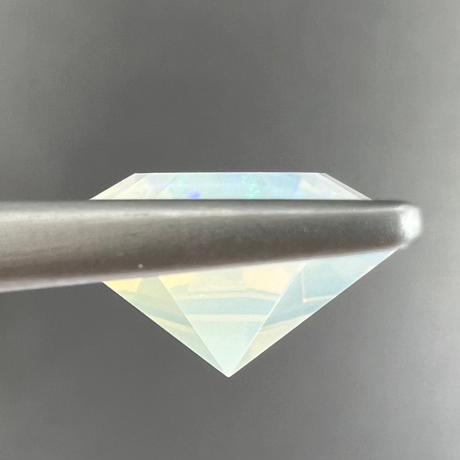 A loose, faceted octagon cut Mexican fire opal gemstone.  The stone is a light yellow color with blue and green fire.