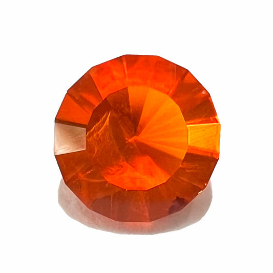 A faceted round cut natural Mexican fire opal stone.  The stone is bright orange in color.