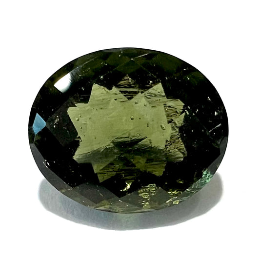 A faceted oval checkerboard cut moldavite gemstone that weighs 4.14 carats.