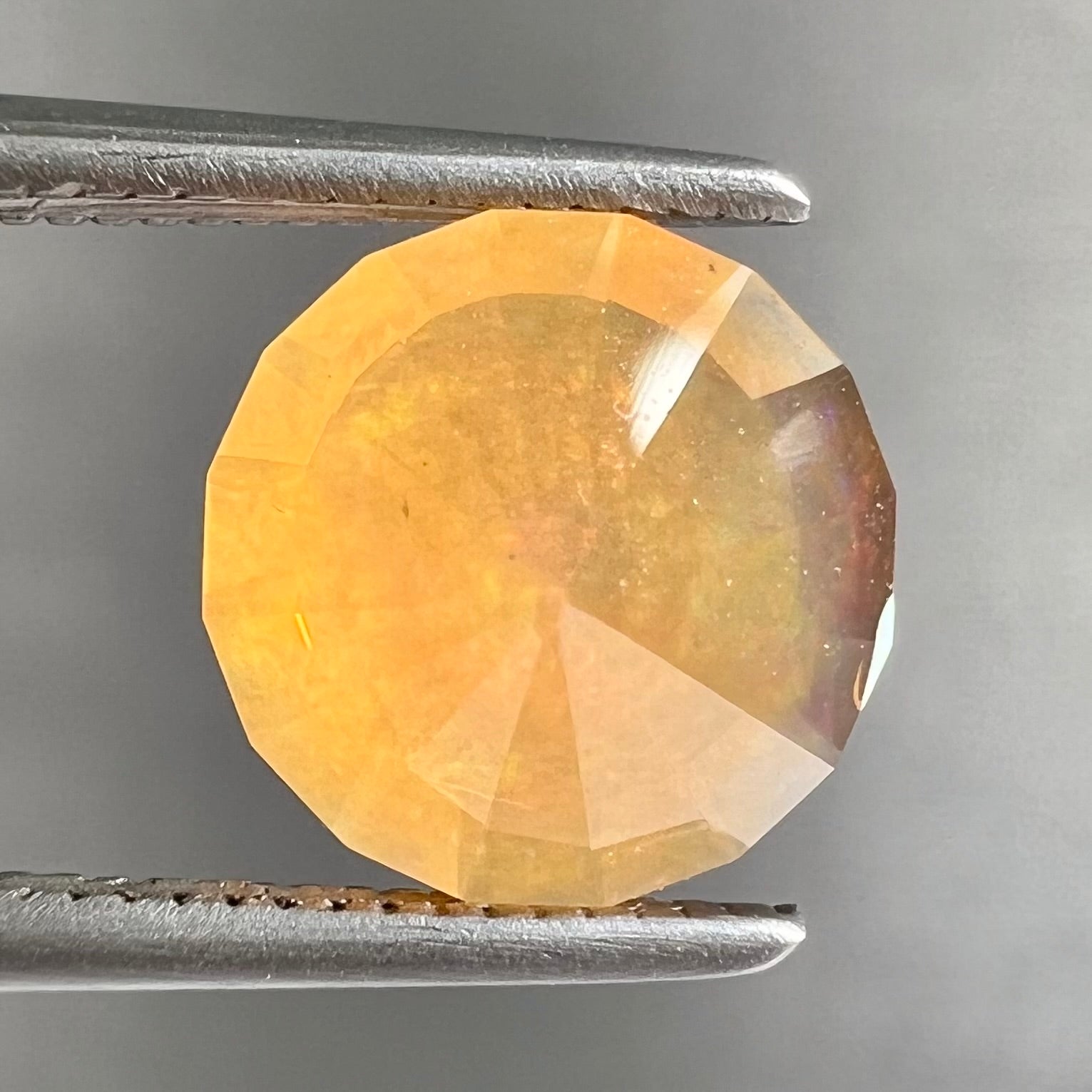 A loose, faceted round cut fire opal from Mexico.  The stone is yellow orange in body color.