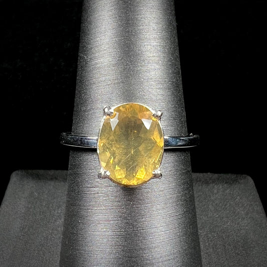 A silver solitaire ring prong-set with a natural, faceted oval cut Mexican fire opal.  The stone is a light yellow color.
