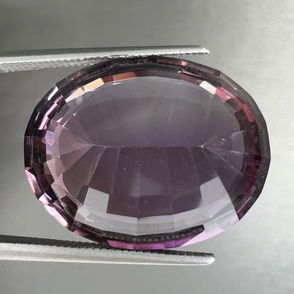 A loose, modified oval cut amethyst gemstone.  The stone is a large size.