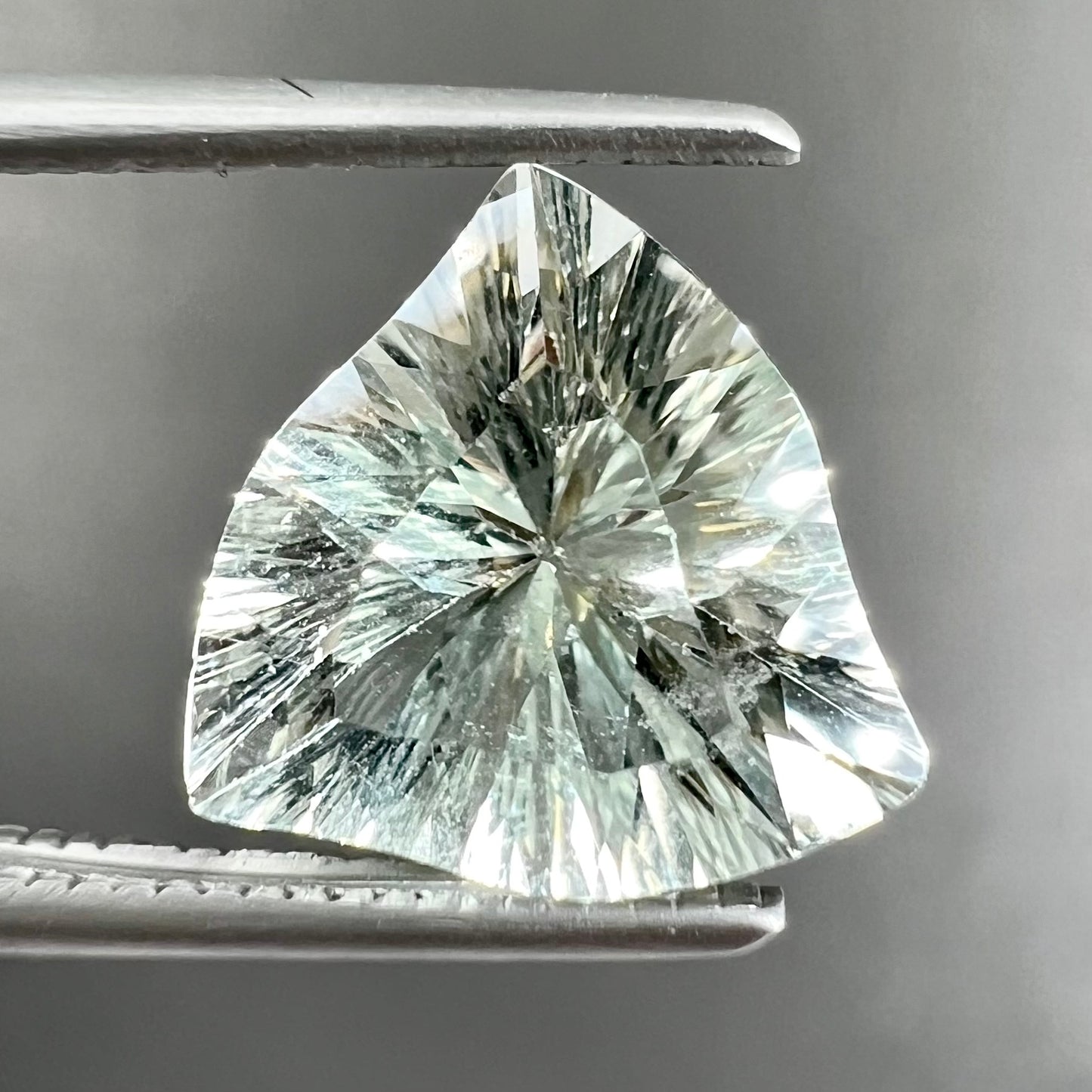 A loose, triangular fantasy cut prasiolite gemstone.  Prasiolite is a light green variety of quartz.