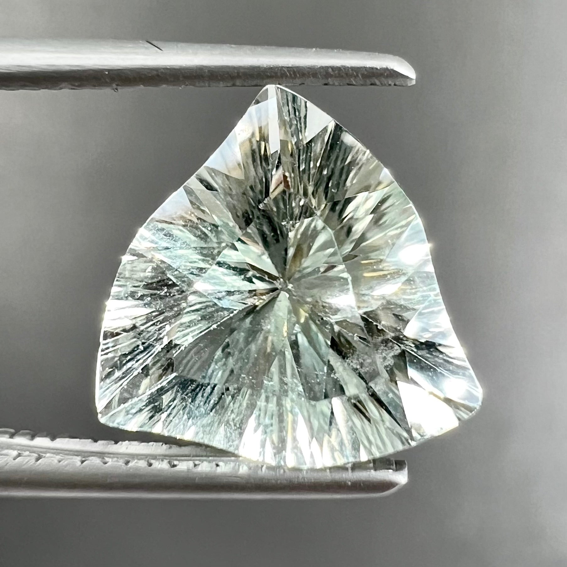 A loose, triangular fantasy cut prasiolite gemstone.  Prasiolite is a light green variety of quartz.