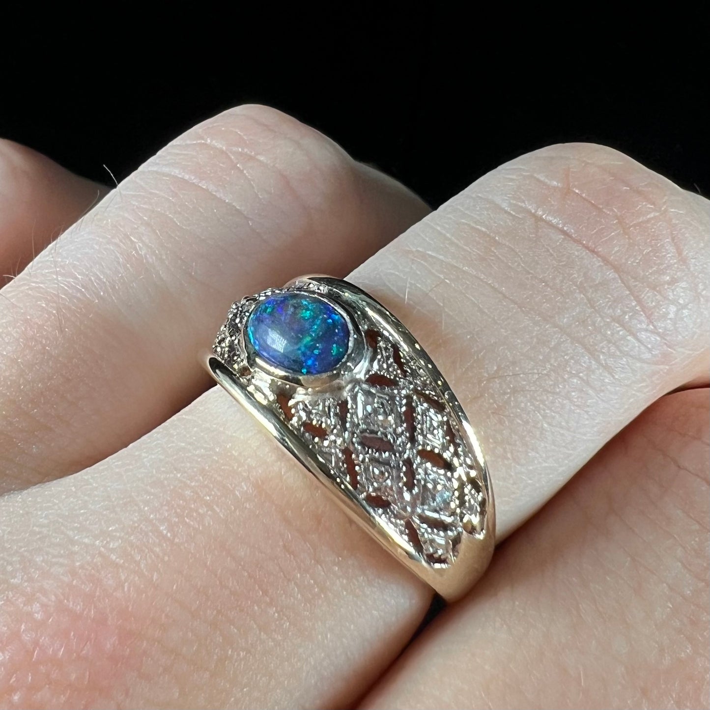 A ladies' yellow gold filigree style ring set with a natural black opal and diamond accents.