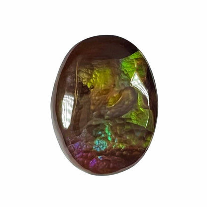 A loose, oval cabochon cut Mexican fire agate.  The stone is predominantly green, teal, blue, and purple.