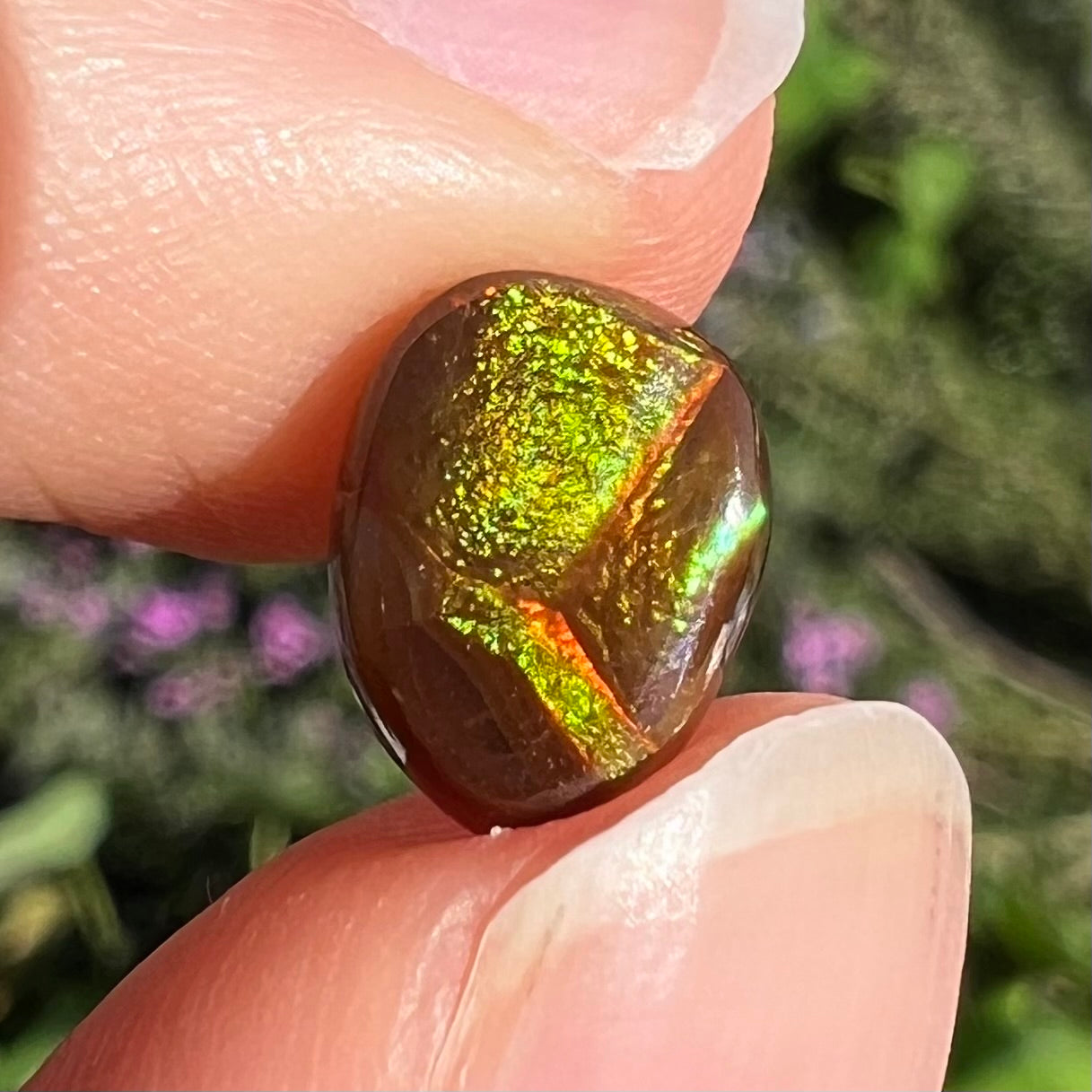 A pear shaped Mexican fire agate cabochon.  The stone has a glittery luster with green and orange colors.