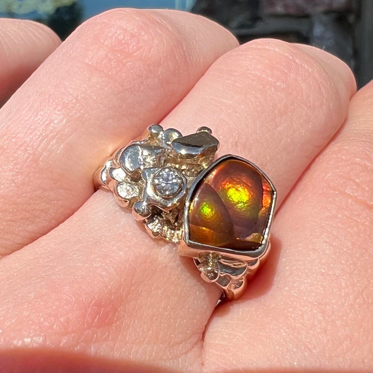 A men's yellow gold, nugget style ring set with a Mexican fire agate stone and a diamond accent.