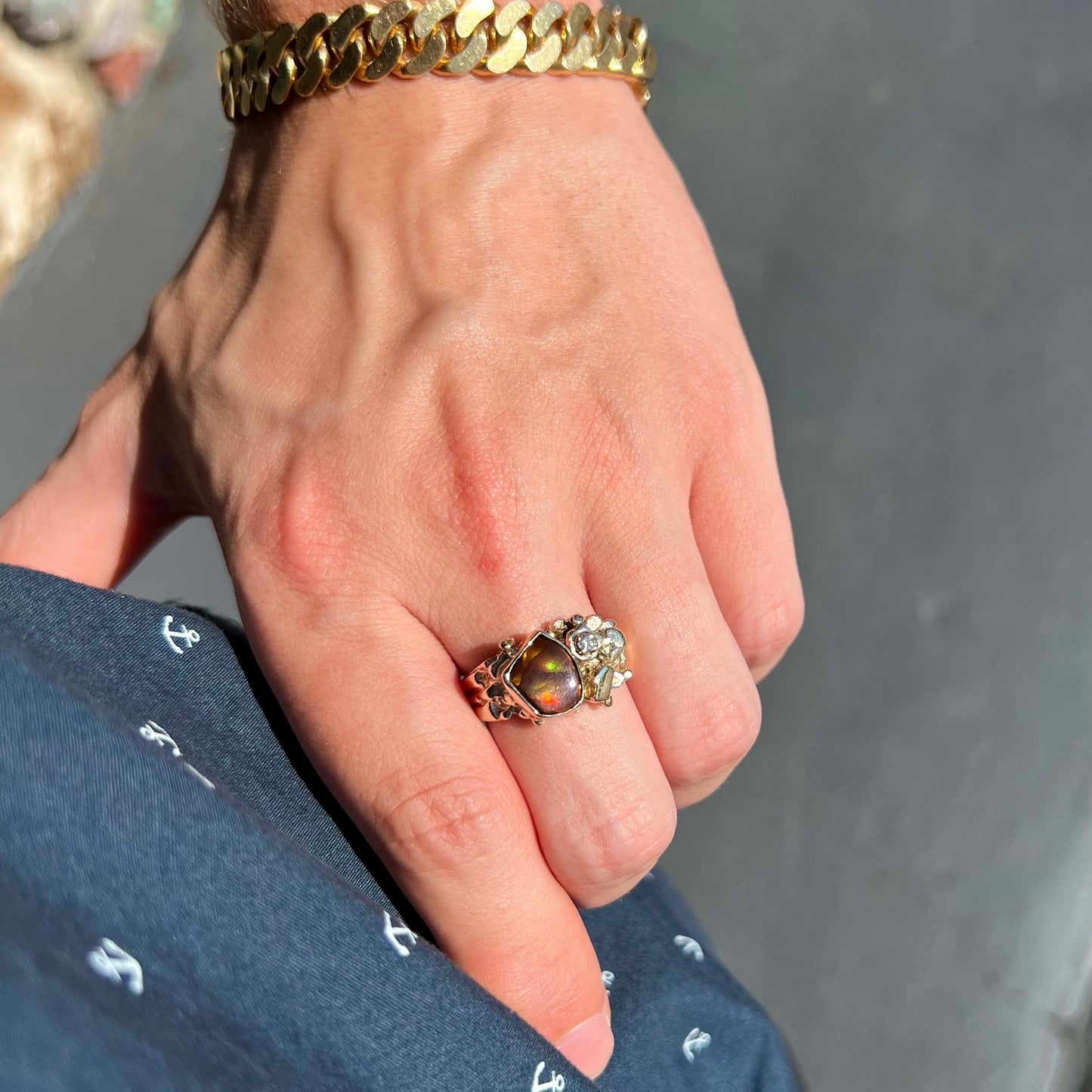 A men's yellow gold, nugget style ring set with a Mexican fire agate stone and a diamond accent.