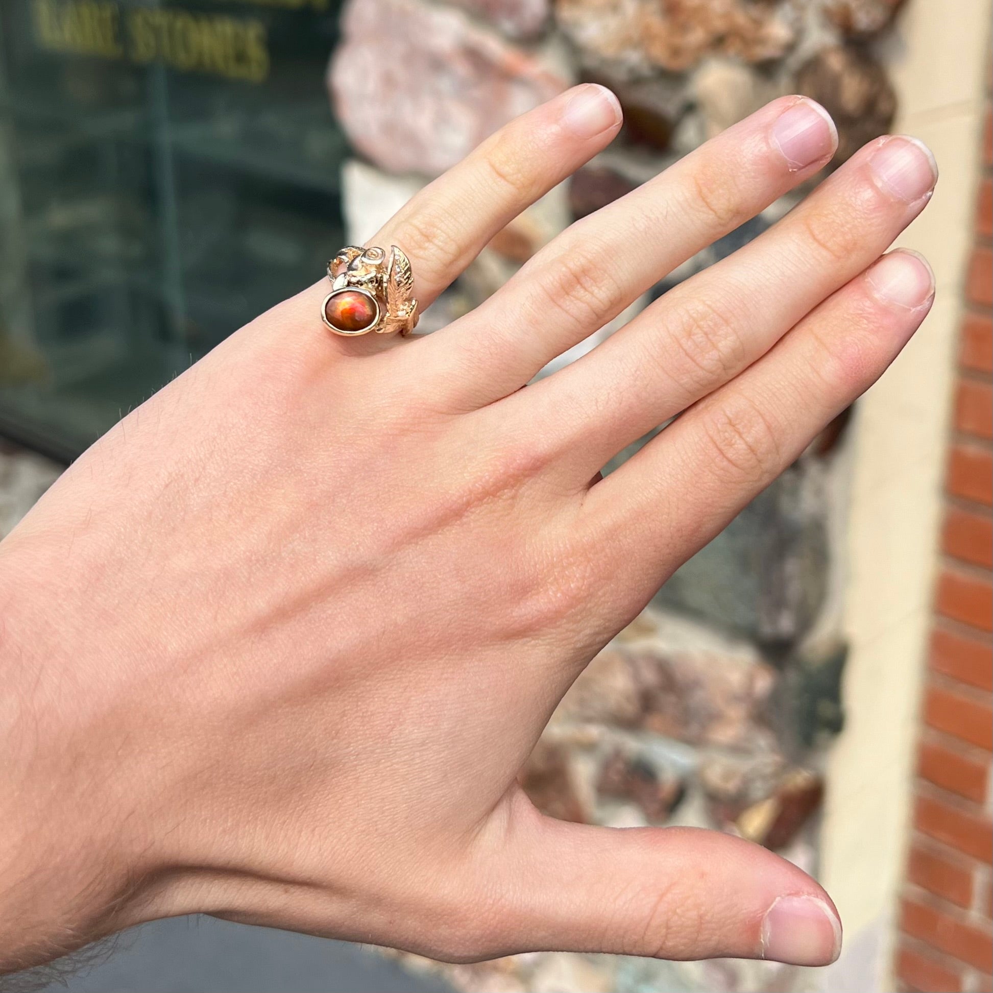 A ladies' yellow gold flower style ring set with an oval cabochon cut fire agate and diamond accents.