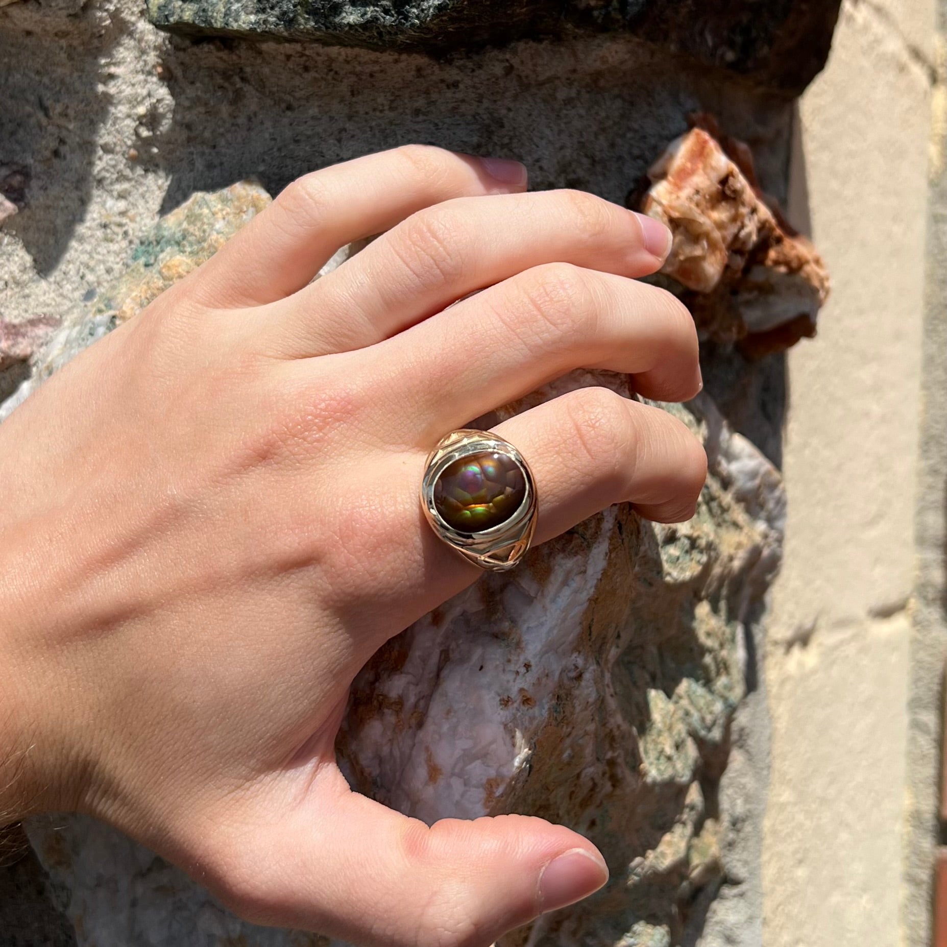 A men's solid yellow gold ring set with a Mexican fire agate stone.  The fire agate has a puple bull's eye pattern.