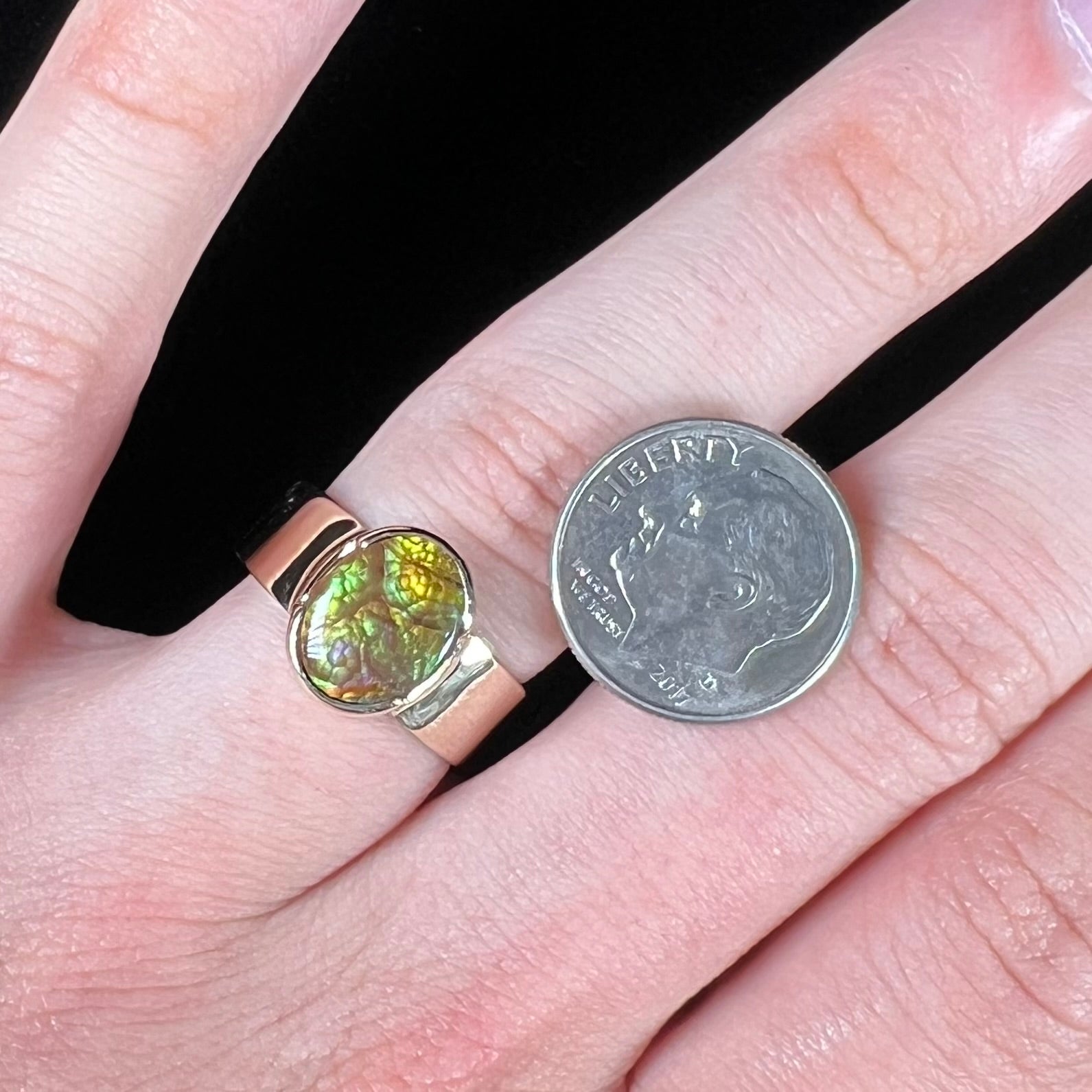 A unisex Mexican fire agate solitaire ring set in yellow gold.  The stone is predominantly green and purple.