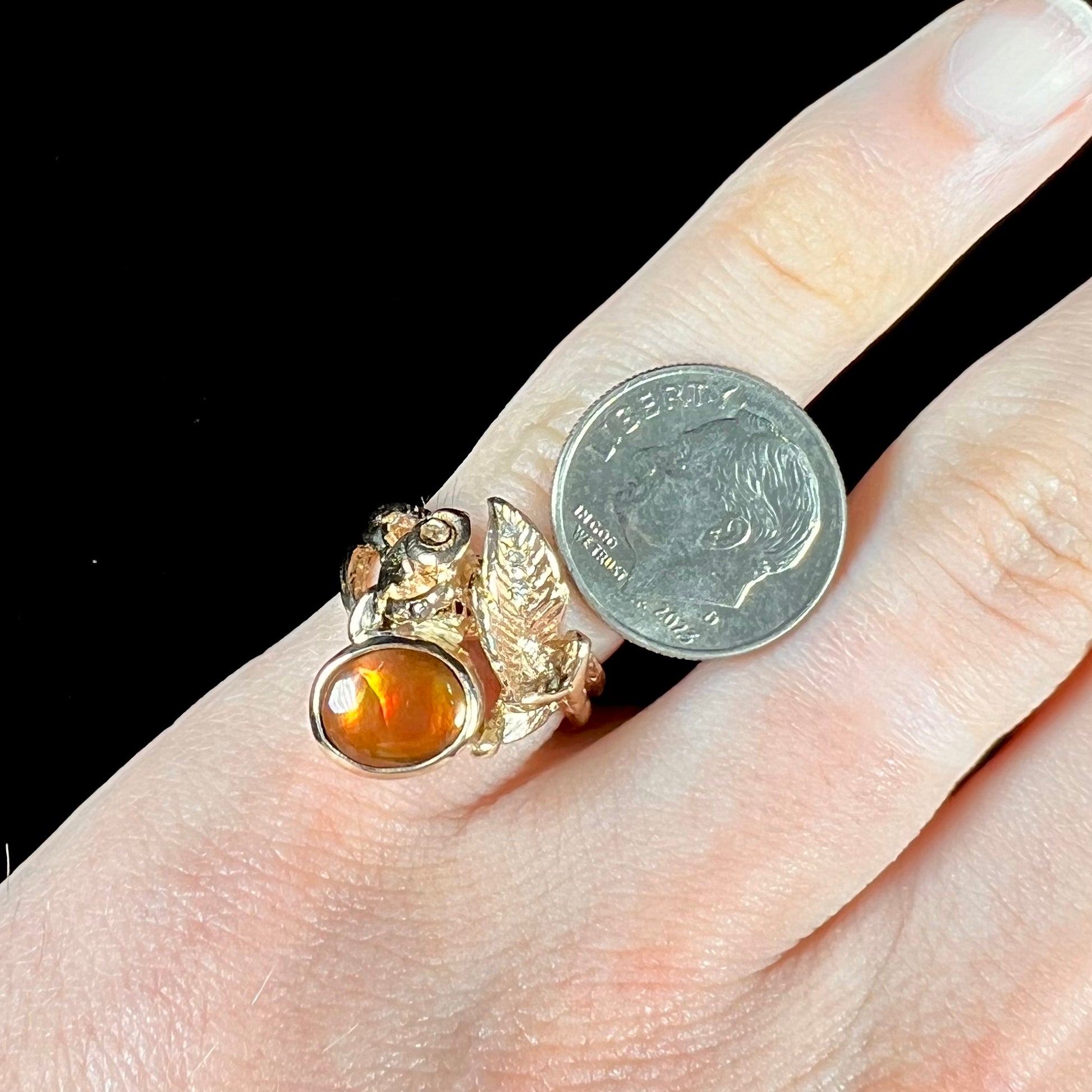 A ladies' yellow gold flower style ring set with an oval cabochon cut fire agate and diamond accents.