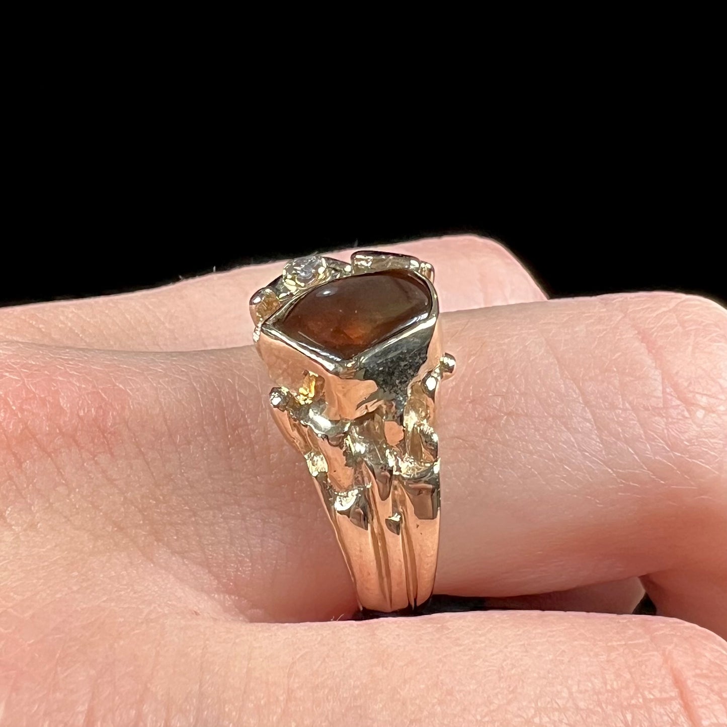 A men's yellow gold, nugget style ring set with a Mexican fire agate stone and a diamond accent.