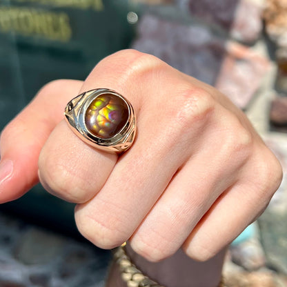 A men's solid yellow gold ring set with a Mexican fire agate stone.  The fire agate has a puple bull's eye pattern.