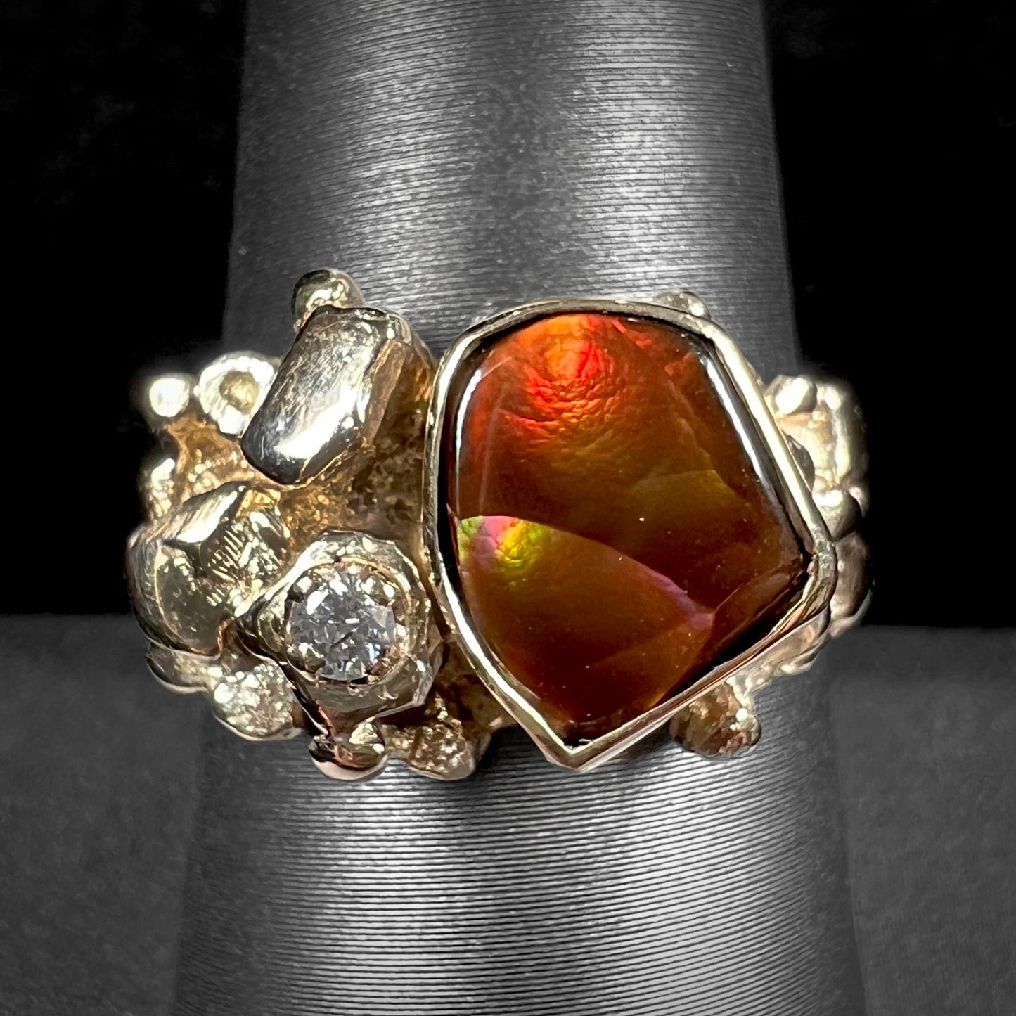 A men's yellow gold, nugget style ring set with a Mexican fire agate stone and a diamond accent.