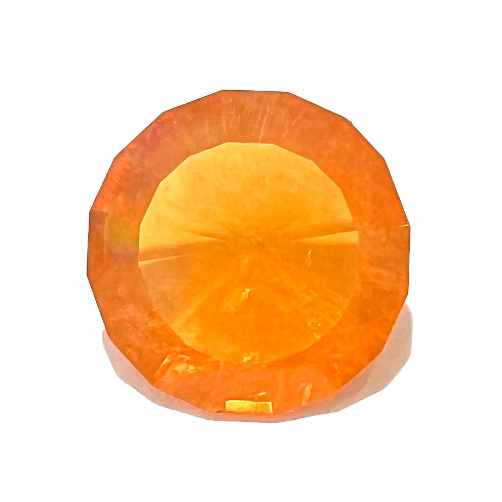 A loose, round faceted cut fire opal from Mexico.  The body color is yellowish orange with red, green, and yellow fire.