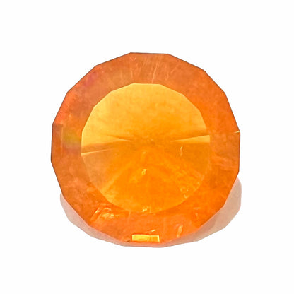 A loose, round faceted cut fire opal from Mexico.  The body color is yellowish orange with red, green, and yellow fire.