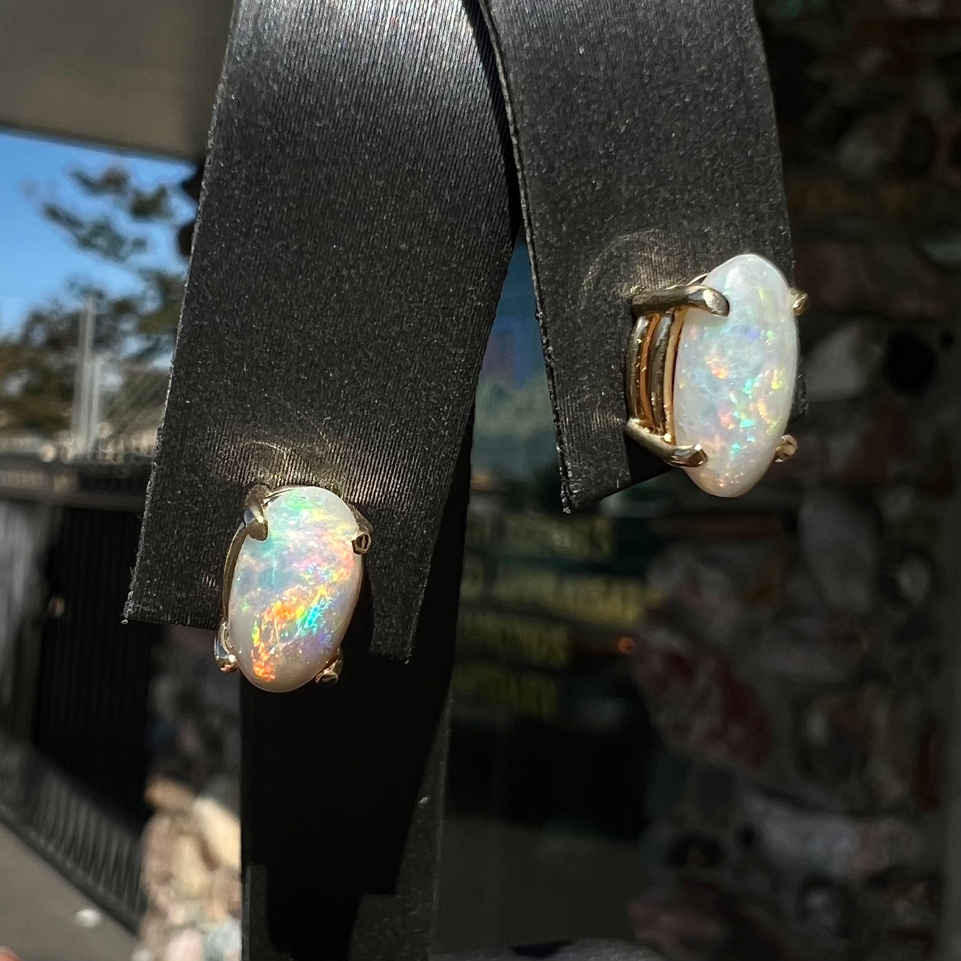 A pair of natural, semi-black crystal opal stud earrings in yellow gold.  The opals are oval cabochon cut.