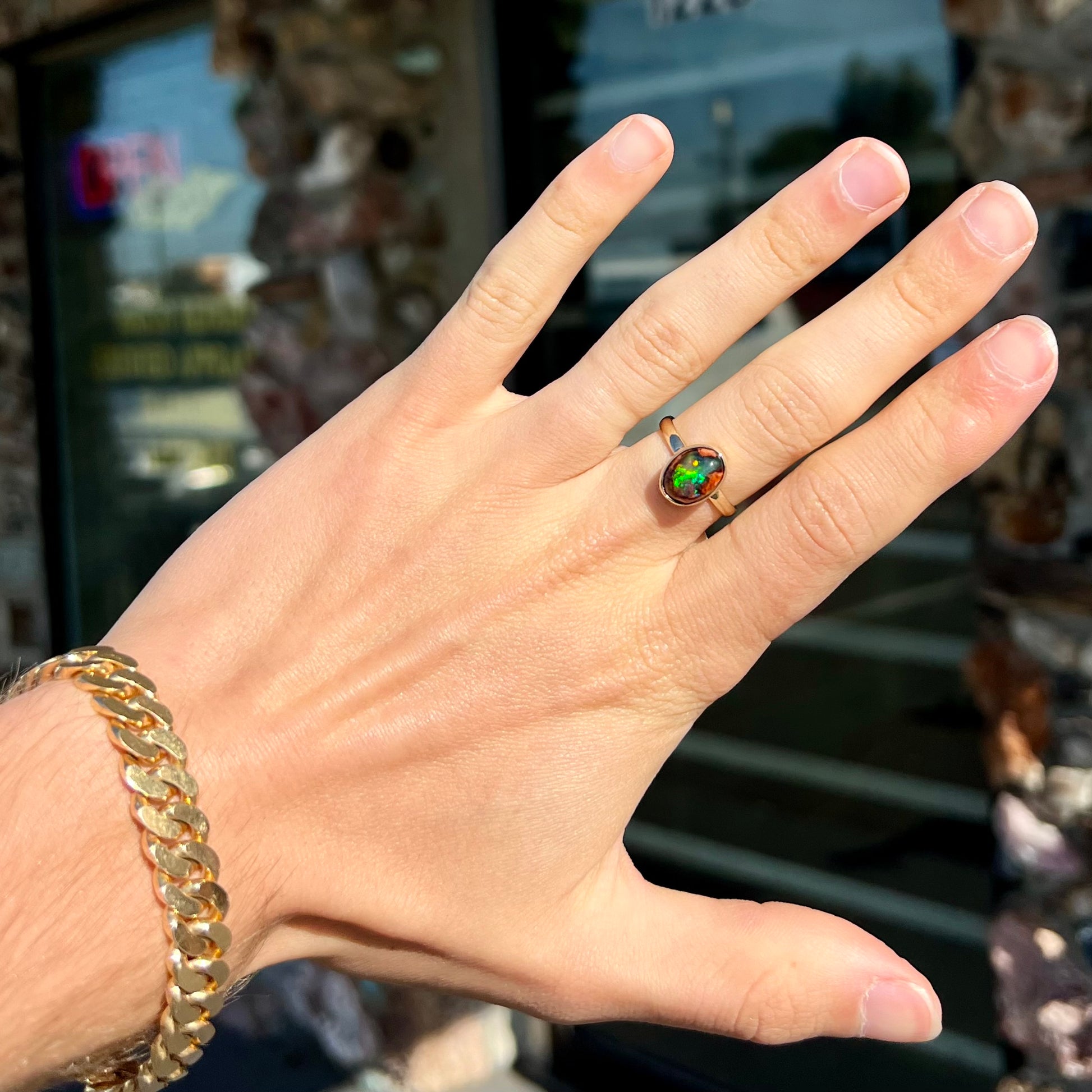 A ladies' yellow gold solitaire ring bezel set with an oval cabochon cut natural black Mexican cantera fire opal stone.