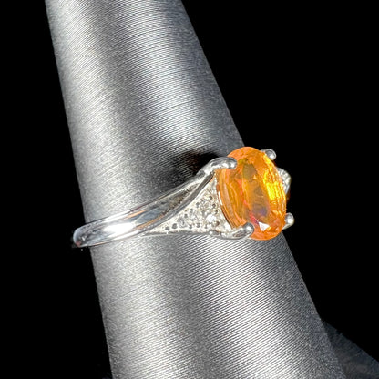 A sterling silver ladies' ring set with a faceted oval cut Mexican fire opal and round white zircon accent stones.
