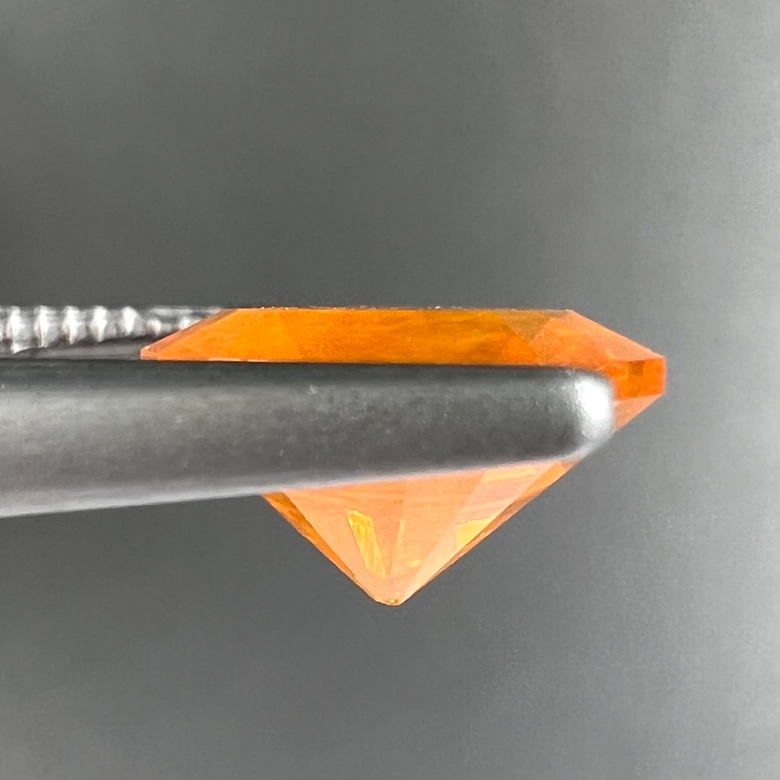 A loose, round faceted cut fire opal from Mexico.  The body color is yellowish orange with red, green, and yellow fire.