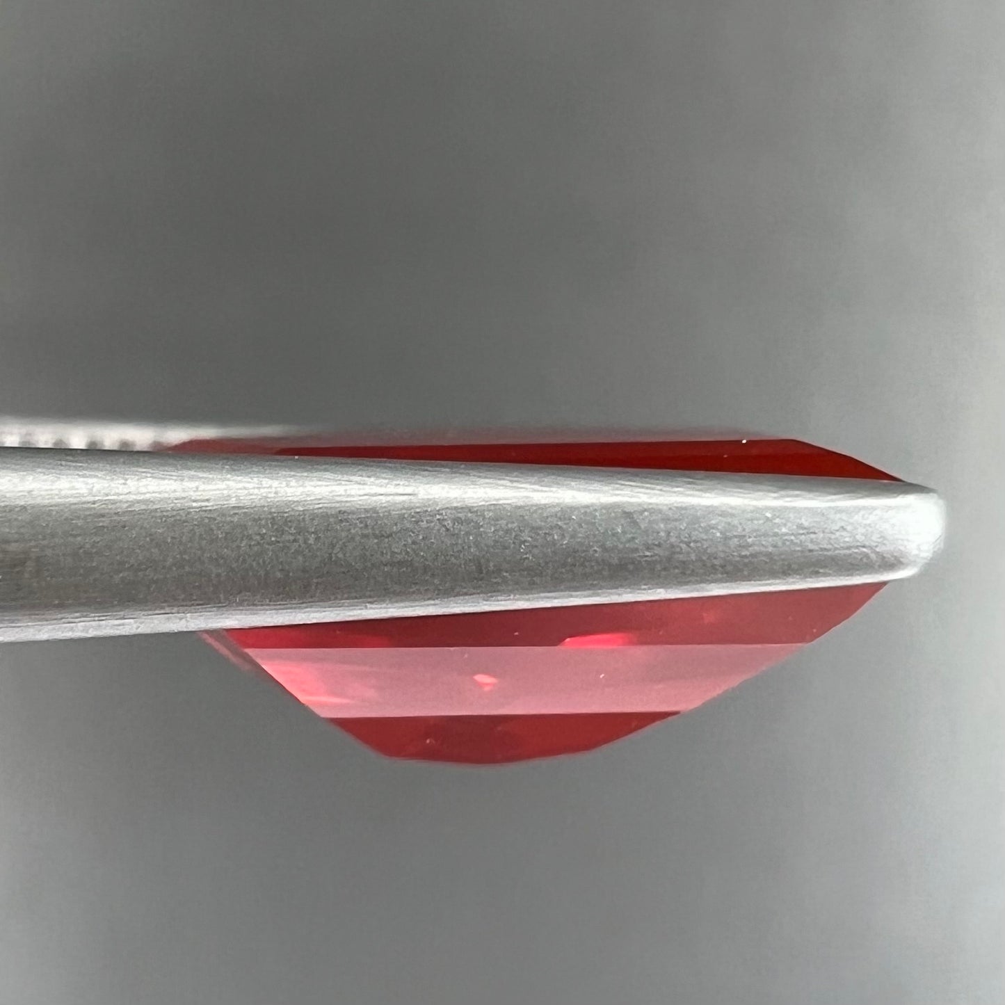 A loose, faceted freeform cut Mexican fire opal gemstone.  The stone is a cherry red color.