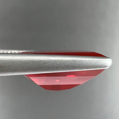 A loose, faceted freeform cut Mexican fire opal gemstone.  The stone is a cherry red color.