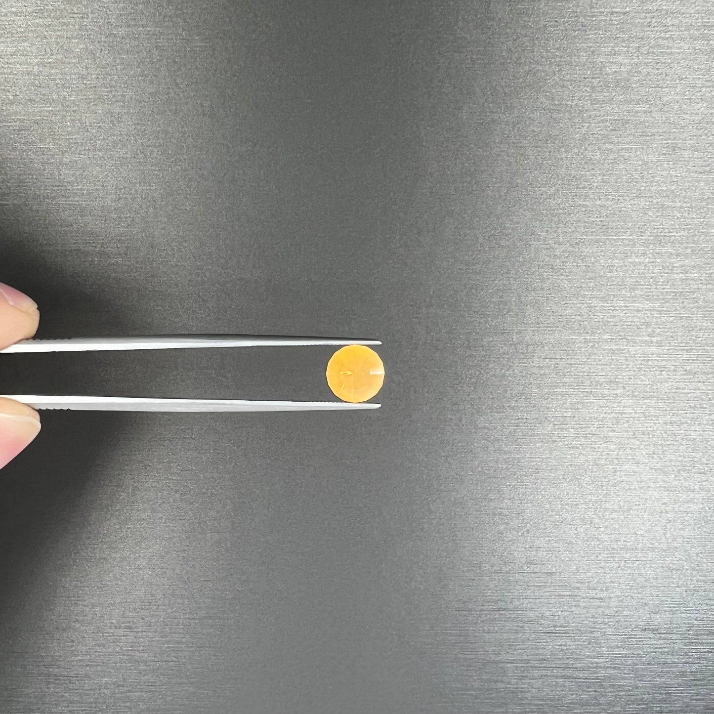 A loose, faceted round cut fire opal from Mexico.  The stone is yellow orange in body color.
