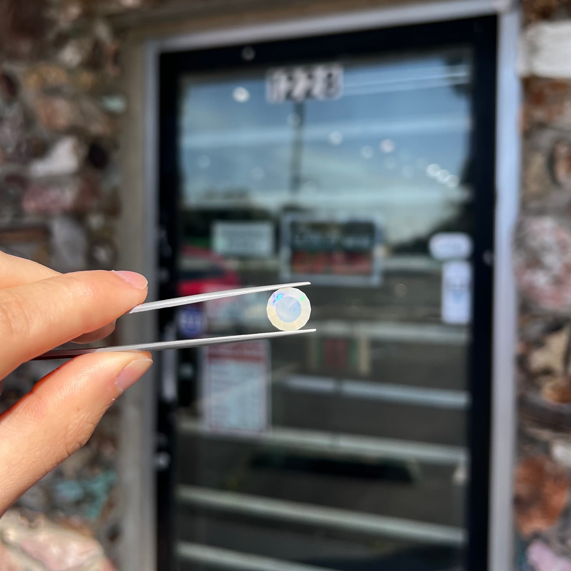 A loose, modified round cut Mexican fire opal gemstone.  The stone is transluscent light yellow with green and blue fire.