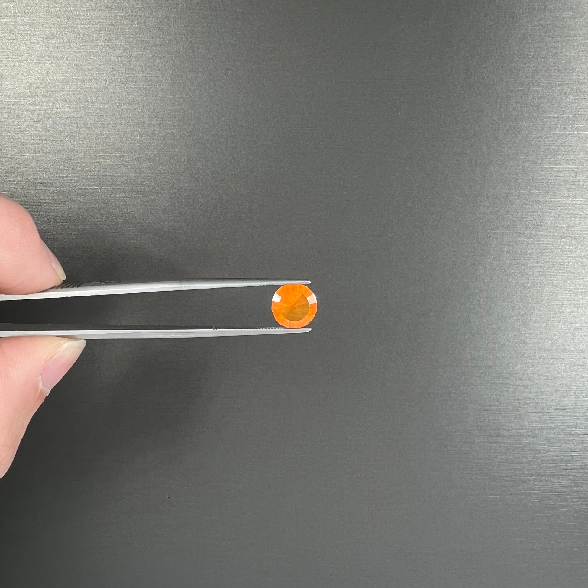 A loose, round faceted cut fire opal from Mexico.  The body color is yellowish orange with red, green, and yellow fire.