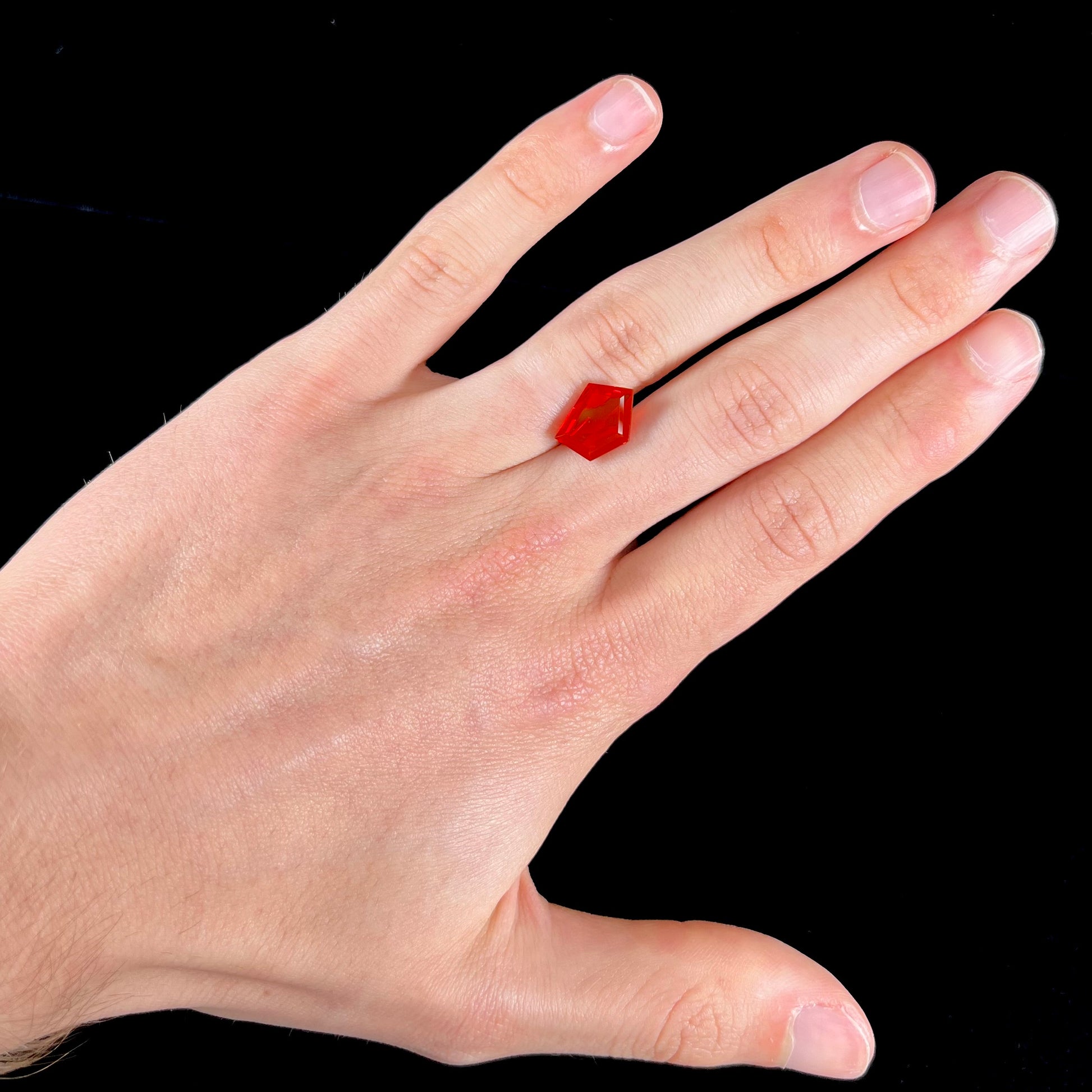 A loose, faceted freeform cut Mexican fire opal gemstone.  The stone is a cherry red color.