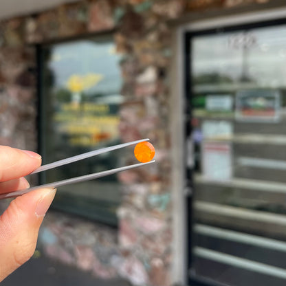 A loose, round faceted cut fire opal from Mexico.  The body color is yellowish orange with red, green, and yellow fire.