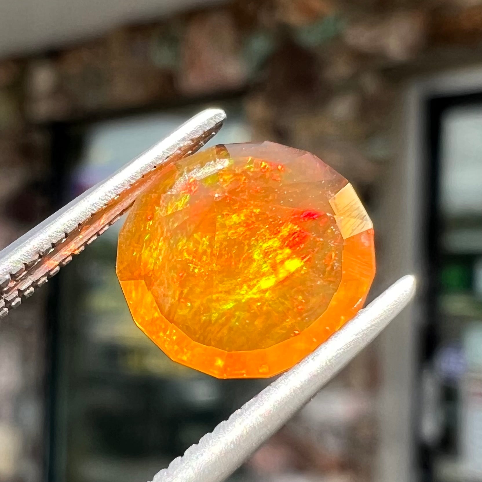 A loose, round faceted cut fire opal from Mexico.  The body color is yellowish orange with red, green, and yellow fire.