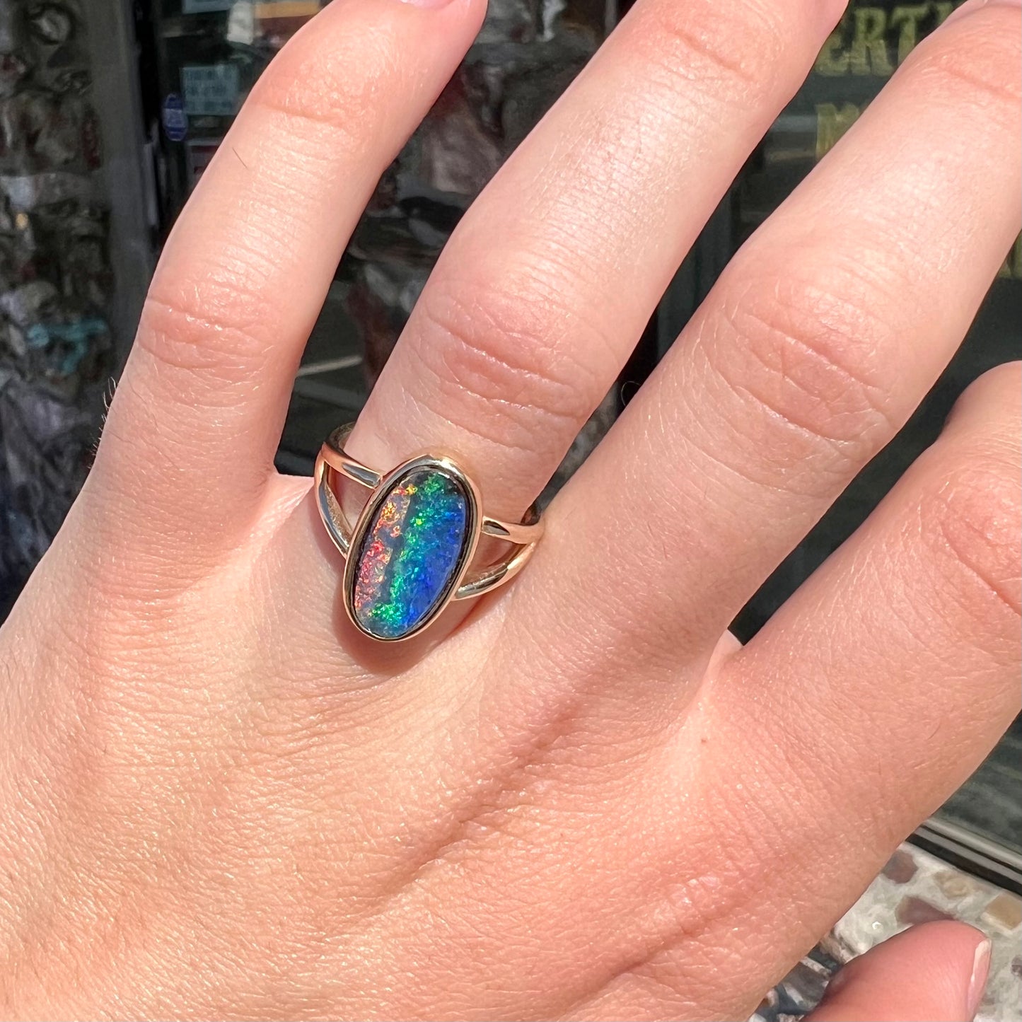 A ladies' yellow gold split shank solitaire ring set with a natural Australian black boulder opal.