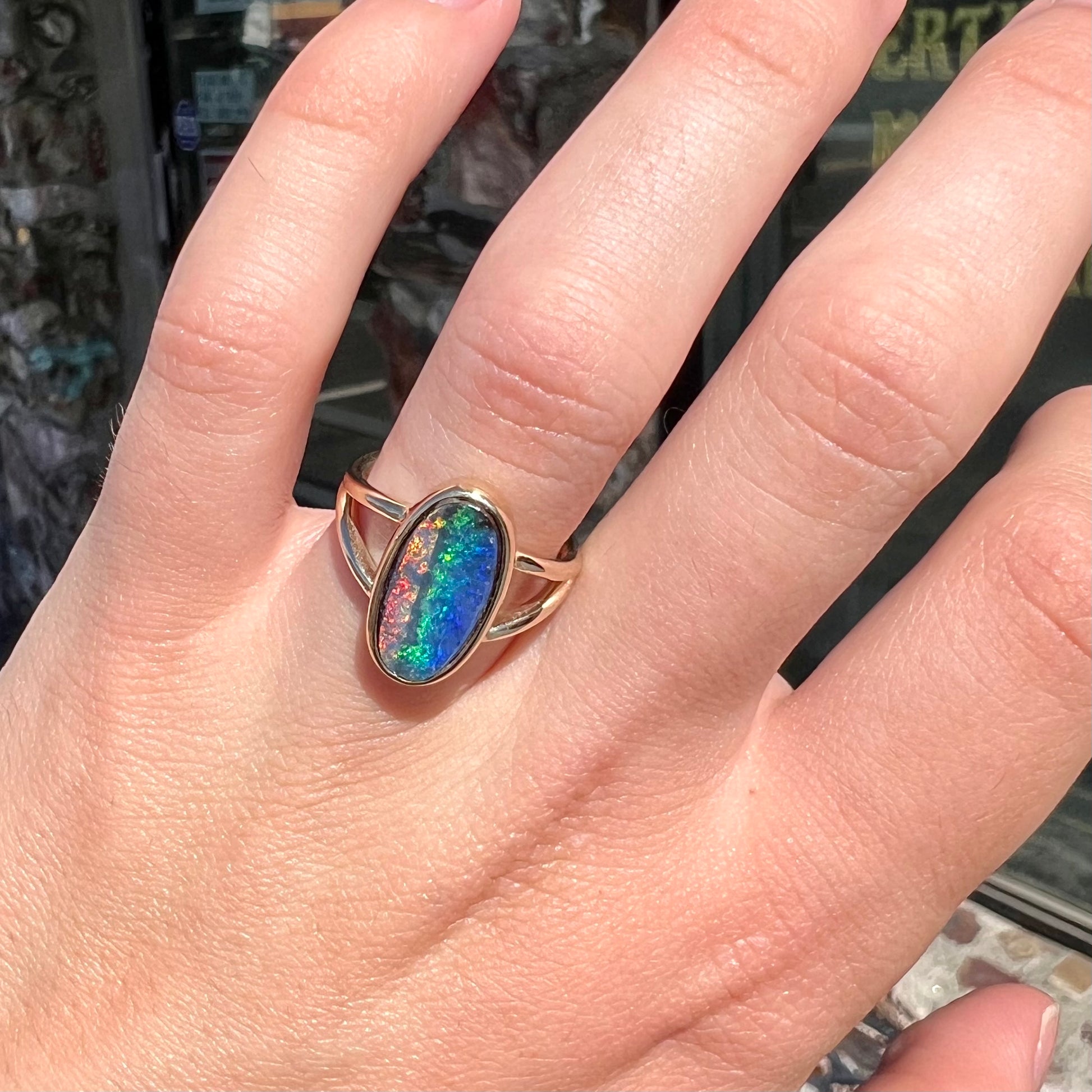A ladies' yellow gold split shank solitaire ring set with a natural Australian black boulder opal.