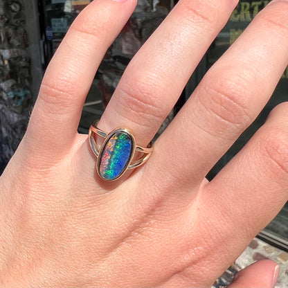 A ladies' yellow gold split shank solitaire ring set with a natural Australian black boulder opal.