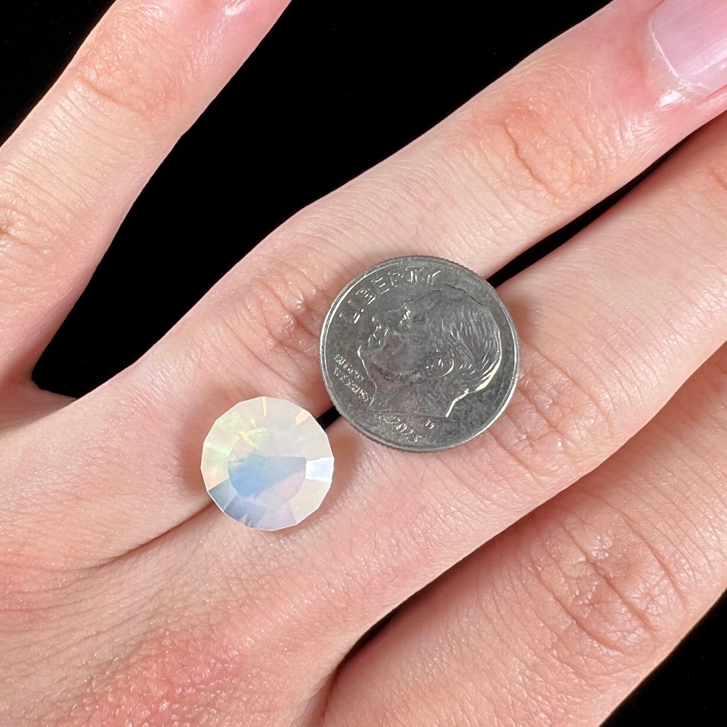 A loose, modified round cut Mexican fire opal gemstone.  The stone is transluscent light yellow with green and blue fire.