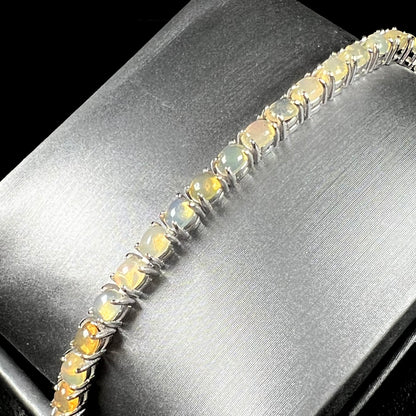 A ladies' sterling silver tennis style bracelet set with natural orange yellow Mexican fire opals.