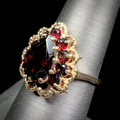 A vintage, 1940's style yellow gold ring set with a pear shaped almandine garnet.  A halo of round garnets surround the center stone.