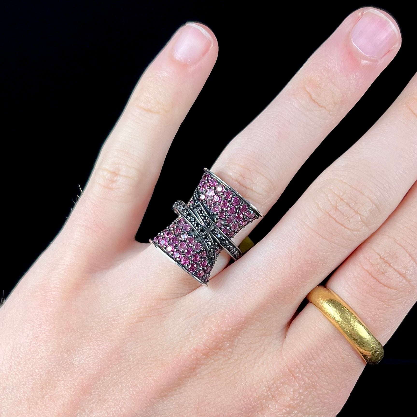 A ladies' bow-shaped designer ring pave set with purple rhodolite garnets and black spinel accents.
