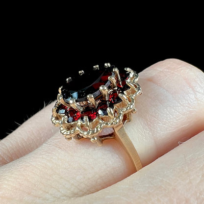 A vintage, 1940's style yellow gold ring set with a pear shaped almandine garnet.  A halo of round garnets surround the center stone.