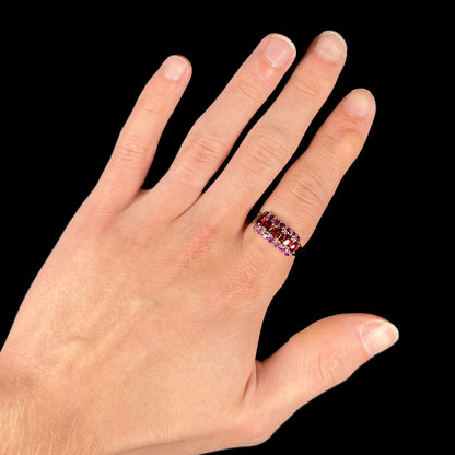 A gold ring set with buff cut cushion shaped almandine garnets with round cut purple rhodolite garnet accents.